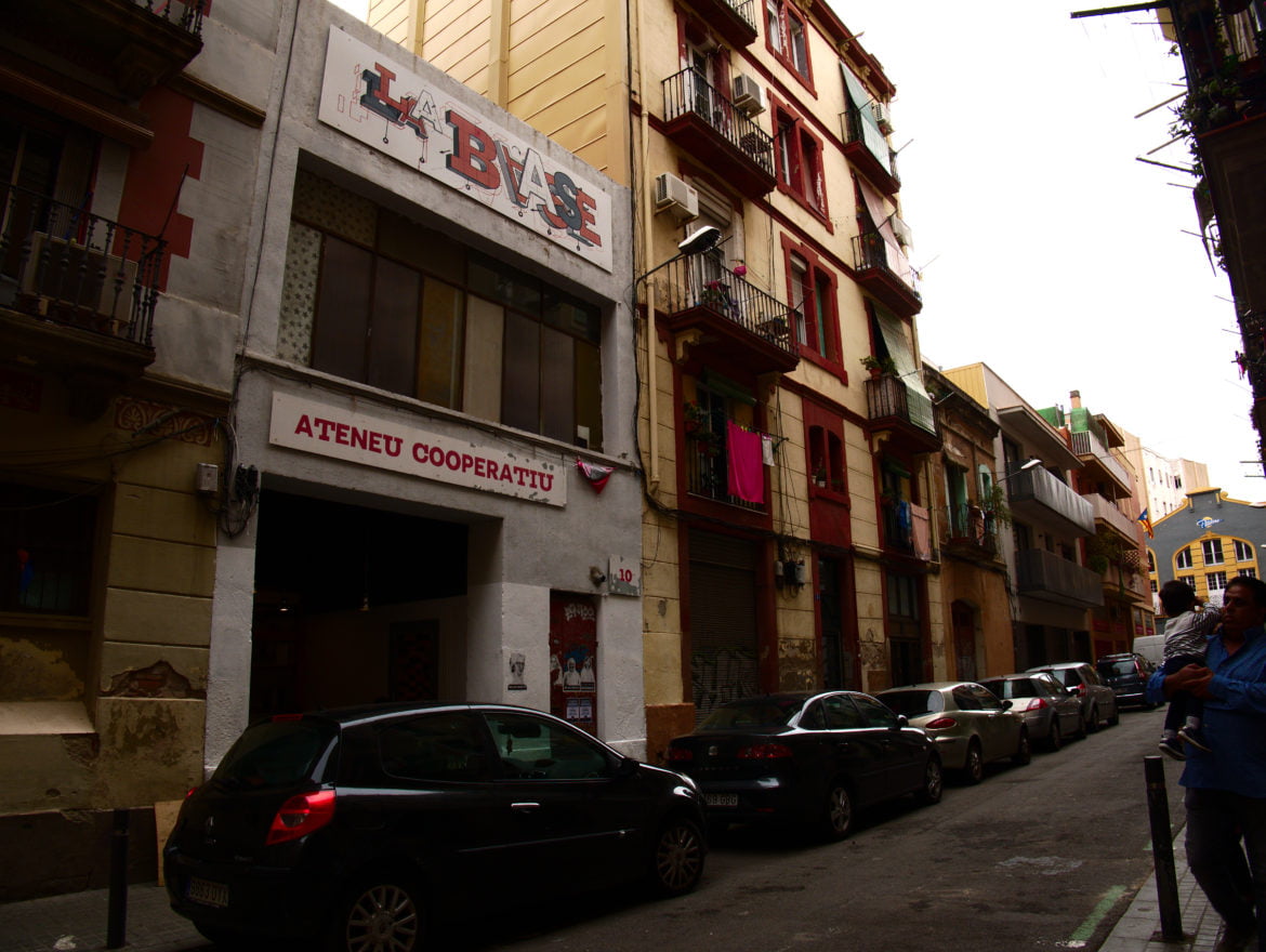 picture of la base in Barcelona with cars in front and a man and child on the right